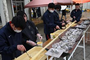 長いバームクーヘンを焼く生徒の写真