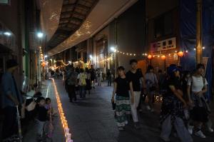 暗い商店街にぼんぼりと提灯の灯りがともっている写真